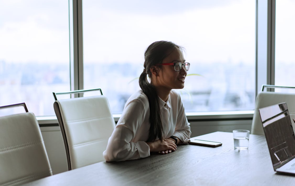 A Smiling Female Corporate Employee Sitting Inside an Office