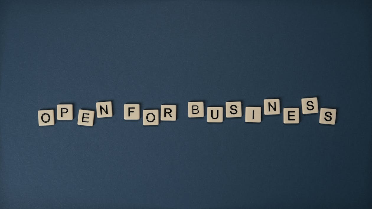 Scrabble-style Letter Tiles Arranged on a Dark Blue Background Spelling Out "OPEN FOR BUSINESS".